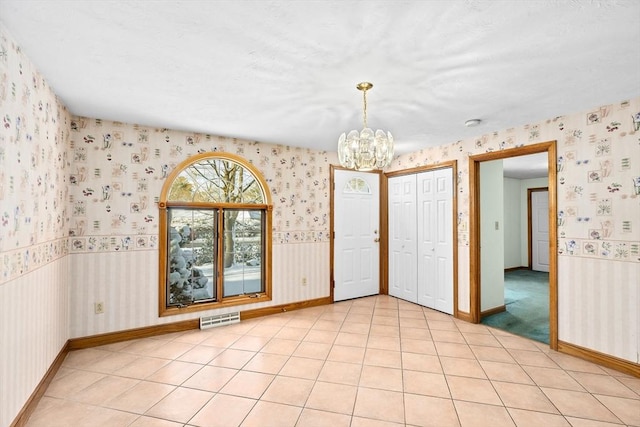 tiled empty room with an inviting chandelier