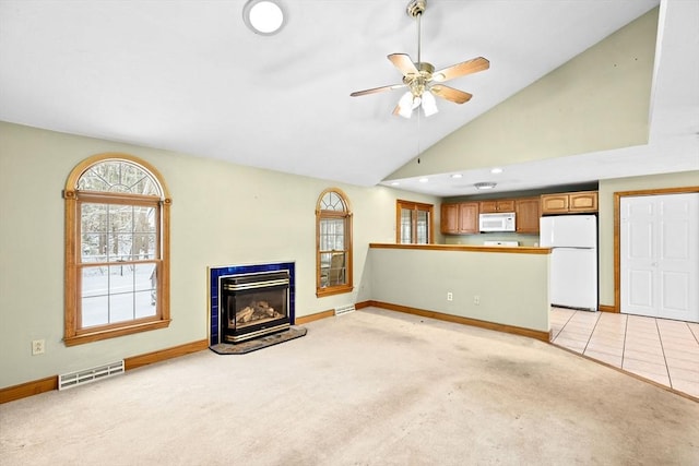 unfurnished living room with ceiling fan, light colored carpet, and high vaulted ceiling