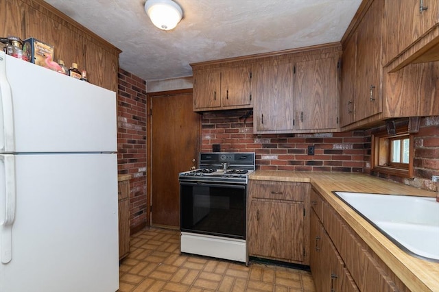 397 Elm St, Braintree, MA 02184 - kitchen with freestanding refrigerator, gas range oven, brick patterned floors, light countertops, and a sink