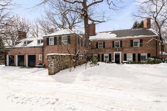 view of front of home featuring an attached garage, a chimney, and brick siding