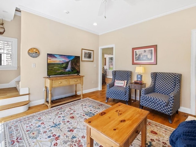 living area with ornamental molding, healthy amount of natural light, baseboards, wood finished floors, and a ceiling fan