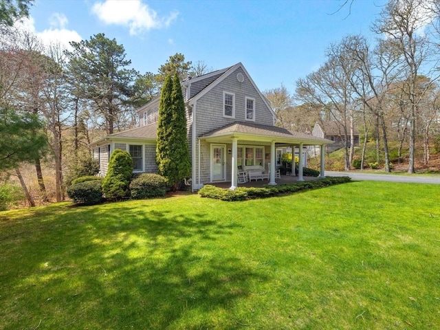 shingle-style home featuring covered porch and a front lawn