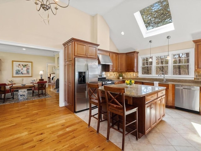 kitchen with stainless steel appliances, exhaust hood, a sink, a kitchen island, and decorative backsplash