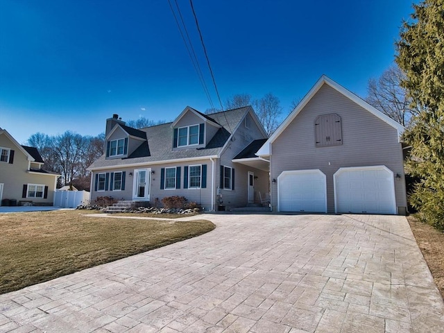 cape cod home featuring a garage, fence, decorative driveway, a front lawn, and a chimney