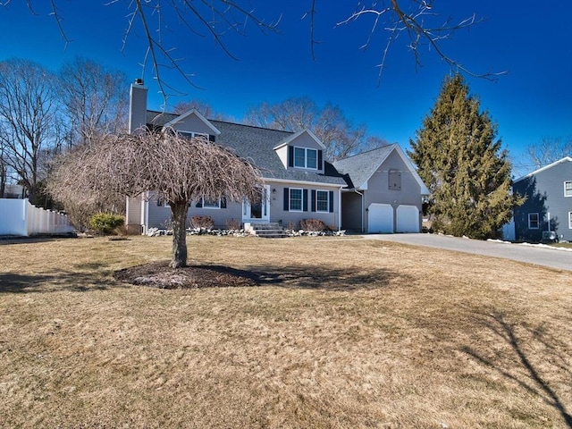 new england style home featuring driveway, fence, and a front lawn