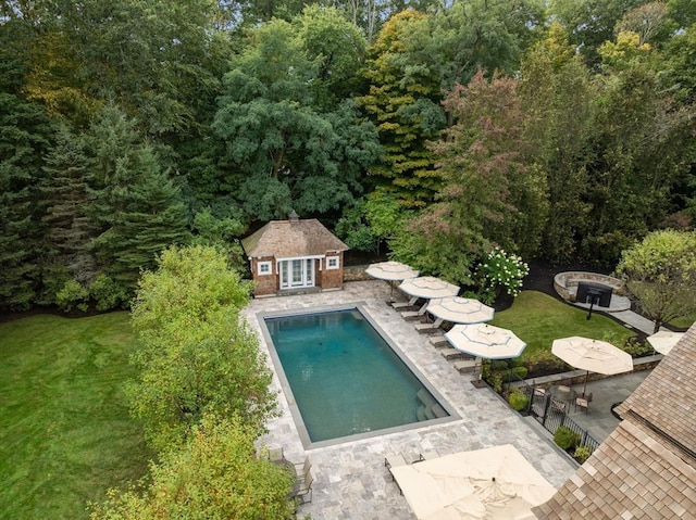 view of pool with an outbuilding, a lawn, and a patio