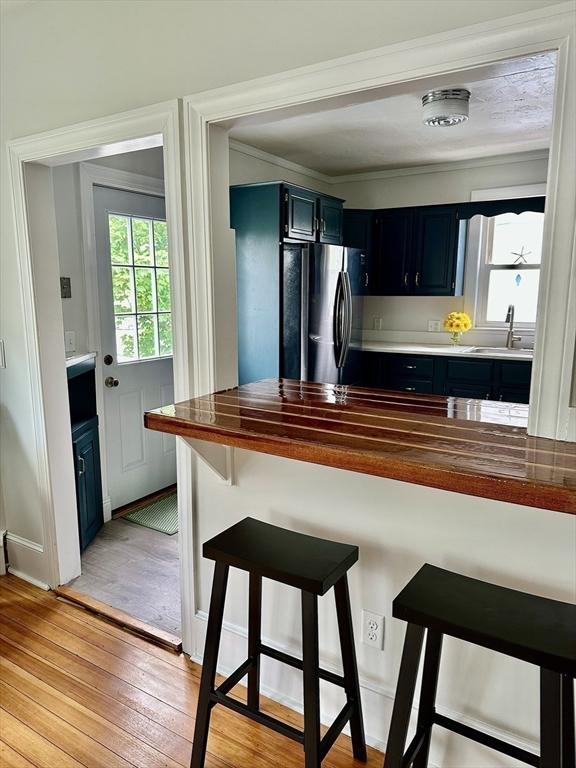 1 S Ave Unit 1, Hull, MA 02045 - kitchen featuring freestanding refrigerator, a breakfast bar, light wood-type flooring, blue cabinets, and dark cabinetry