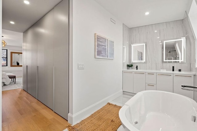 bathroom with hardwood / wood-style flooring, vanity, and a tub