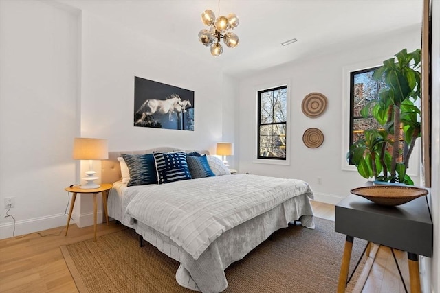 bedroom featuring wood-type flooring and an inviting chandelier