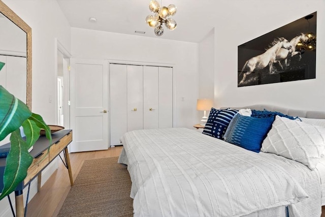 bedroom with a closet, a chandelier, and light wood-type flooring