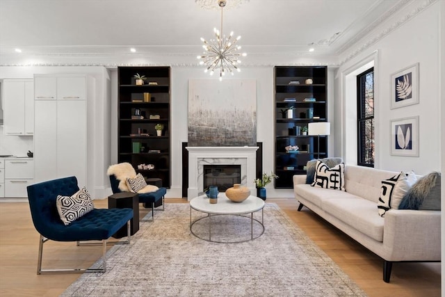 living room featuring a premium fireplace, built in features, a chandelier, and light hardwood / wood-style flooring