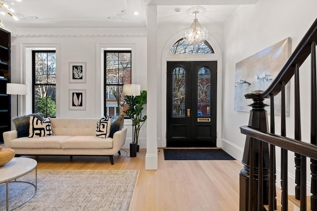 foyer with wood-type flooring, ornamental molding, and an inviting chandelier