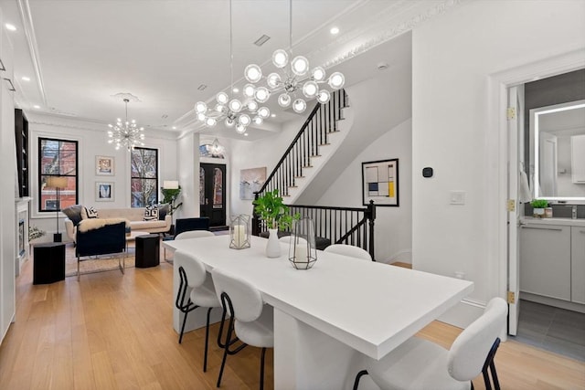 dining space featuring a notable chandelier, crown molding, and light hardwood / wood-style flooring