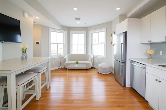 89 Prescott St Unit C, Boston, MA 02128 - kitchen with appliances with stainless steel finishes, light countertops, light wood-type flooring, recessed lighting, and white cabinets