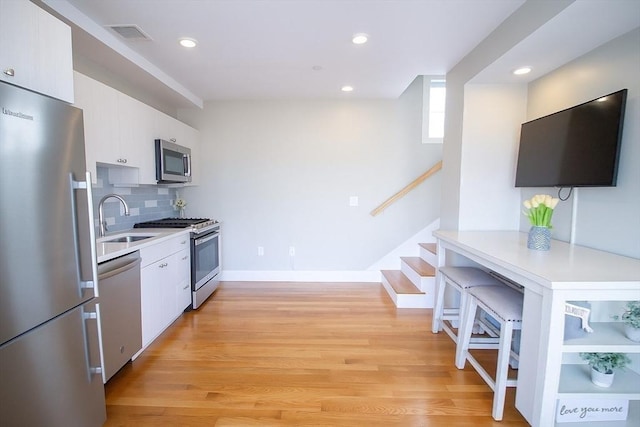 89 Prescott St Unit C, Boston, MA 02128 - kitchen with appliances with stainless steel finishes, white cabinetry, light countertops, light wood-style floors, and recessed lighting