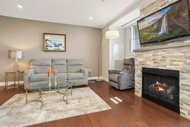 living area with recessed lighting, baseboards, a stone fireplace, and wood finished floors