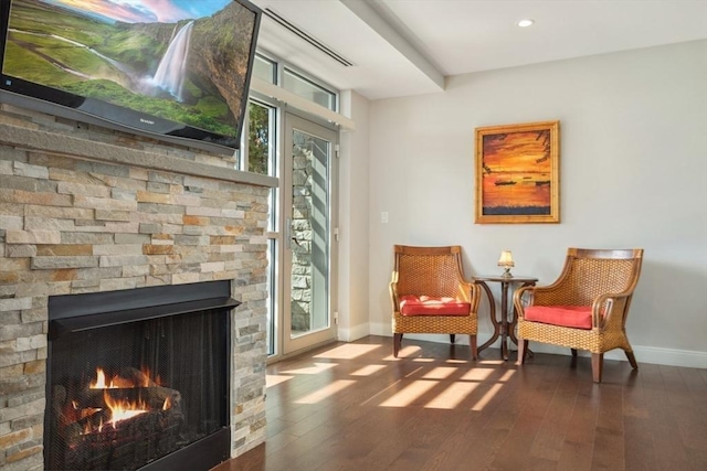 living area with baseboards, plenty of natural light, wood finished floors, and a fireplace