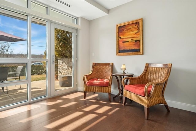 living area with plenty of natural light, baseboards, and wood finished floors