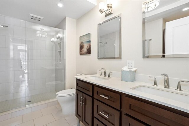 bathroom with double vanity, a stall shower, toilet, and a sink