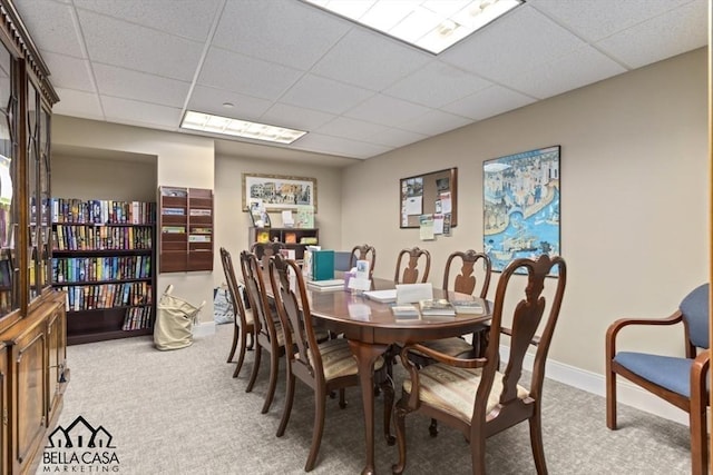 dining area with a drop ceiling, baseboards, and carpet flooring