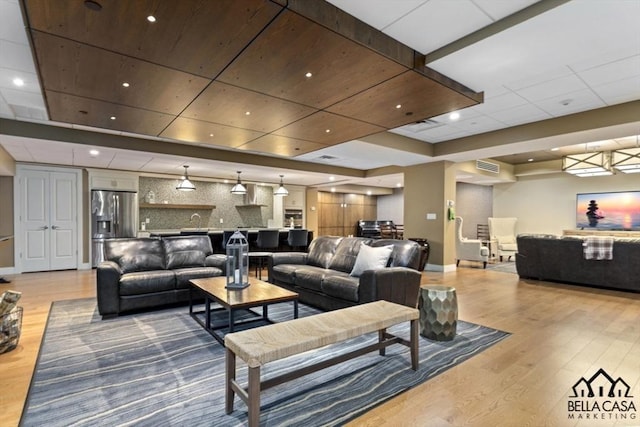 living room with recessed lighting, light wood-style floors, baseboards, and a drop ceiling