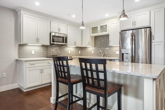 kitchen with backsplash, a breakfast bar area, stainless steel appliances, white cabinetry, and dark wood-style flooring