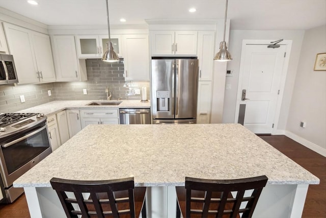 kitchen with decorative backsplash, white cabinetry, appliances with stainless steel finishes, and a sink