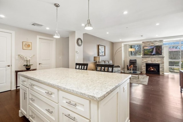 kitchen with recessed lighting, visible vents, dark wood-type flooring, and a stone fireplace