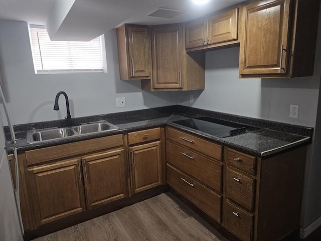 kitchen featuring black electric stovetop, dark hardwood / wood-style floors, sink, and dark stone counters