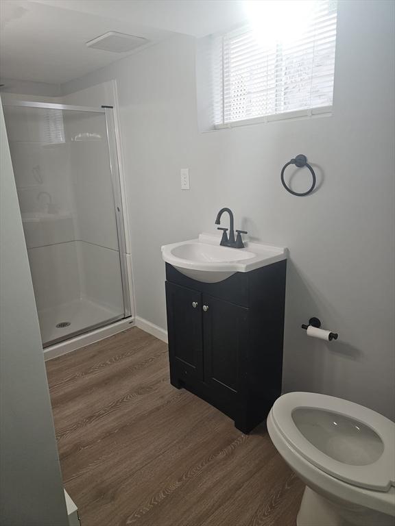 bathroom with walk in shower, wood-type flooring, toilet, and vanity