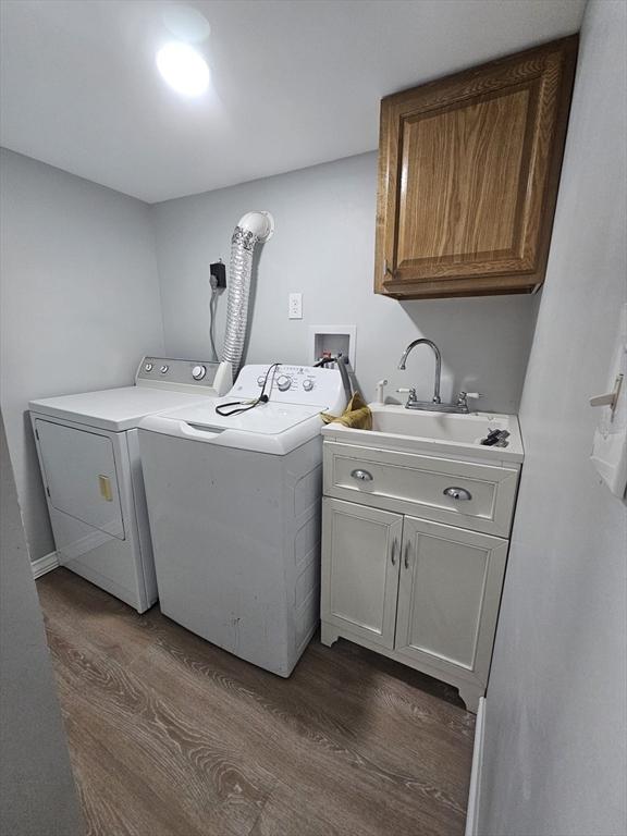 laundry area with sink, dark wood-type flooring, washing machine and dryer, and cabinets