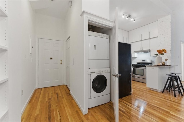69 Harvey St Unit 1, Cambridge, MA 02140 - laundry area with stacked washer / drying machine, light wood-style floors, rail lighting, and baseboards