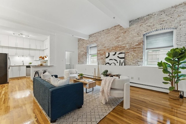 69 Harvey St Unit 1, Cambridge, MA 02140 - living room with a baseboard heating unit, light wood-type flooring, beamed ceiling, and rail lighting
