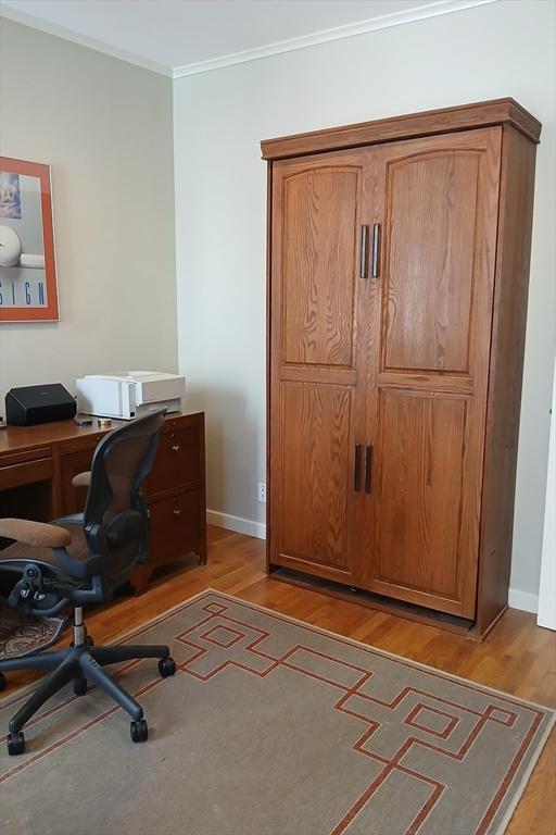office area with baseboards, ornamental molding, and light wood finished floors