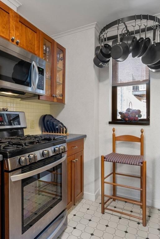 kitchen with decorative backsplash, stainless steel appliances, brown cabinetry, and light floors