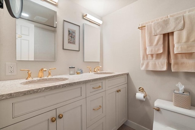 bathroom featuring a sink, baseboards, toilet, and double vanity
