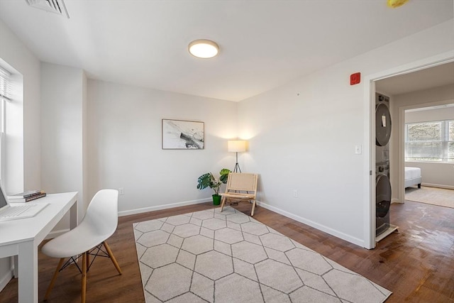 office featuring dark hardwood / wood-style flooring and stacked washer / dryer