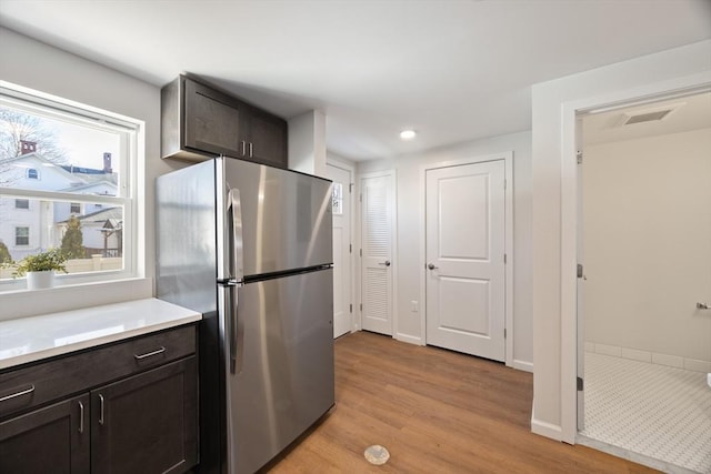 kitchen featuring dark brown cabinets, light wood-type flooring, and stainless steel refrigerator