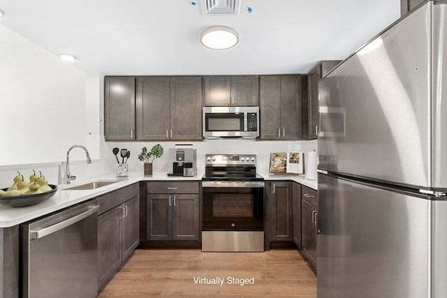 kitchen featuring sink, light hardwood / wood-style floors, dark brown cabinets, and appliances with stainless steel finishes