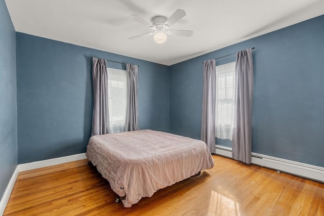 bedroom featuring ceiling fan, a baseboard radiator, and light wood-type flooring