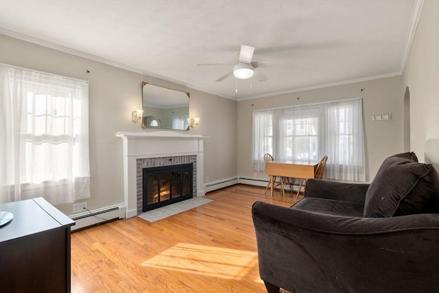 living room featuring a fireplace, a baseboard radiator, ornamental molding, ceiling fan, and light hardwood / wood-style floors