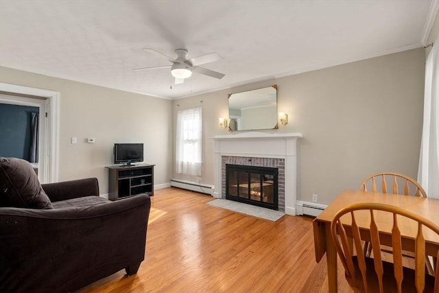 living room with ornamental molding, a fireplace, baseboard heating, and light hardwood / wood-style floors