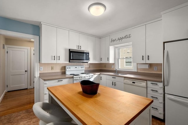 kitchen with white appliances, a kitchen island, and white cabinets