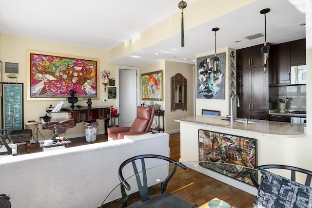 kitchen featuring dark wood finished floors, visible vents, decorative backsplash, white microwave, and a sink