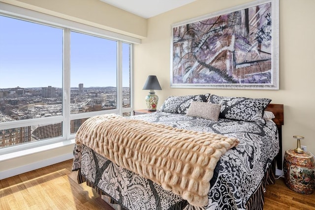 bedroom featuring a view of city, baseboards, and wood finished floors