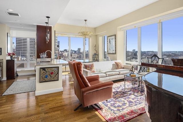 living area with a view of city, wood finished floors, visible vents, and a healthy amount of sunlight