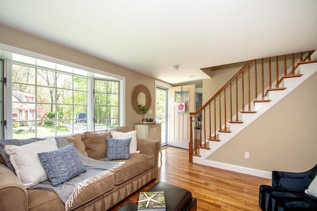 living room featuring baseboards, light wood-style flooring, and stairs