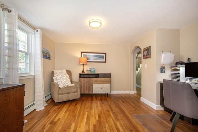 sitting room featuring baseboards, arched walkways, light wood-style flooring, and baseboard heating