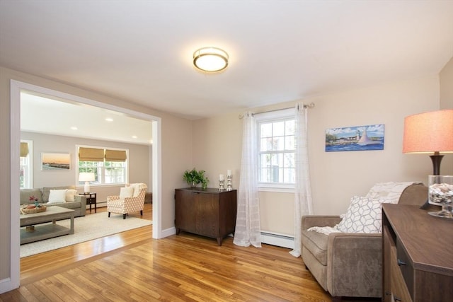 sitting room with baseboards, a baseboard radiator, and light wood-type flooring