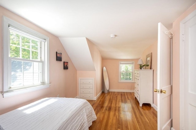 bedroom with baseboards, lofted ceiling, and light wood finished floors
